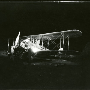 Airplane and men on field, 1930